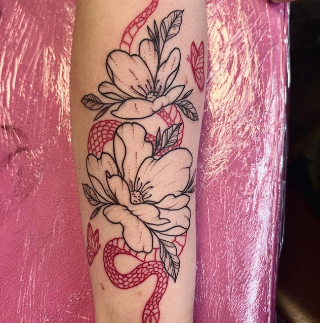 Black and red tattoo of flowers and a red snake on the arm